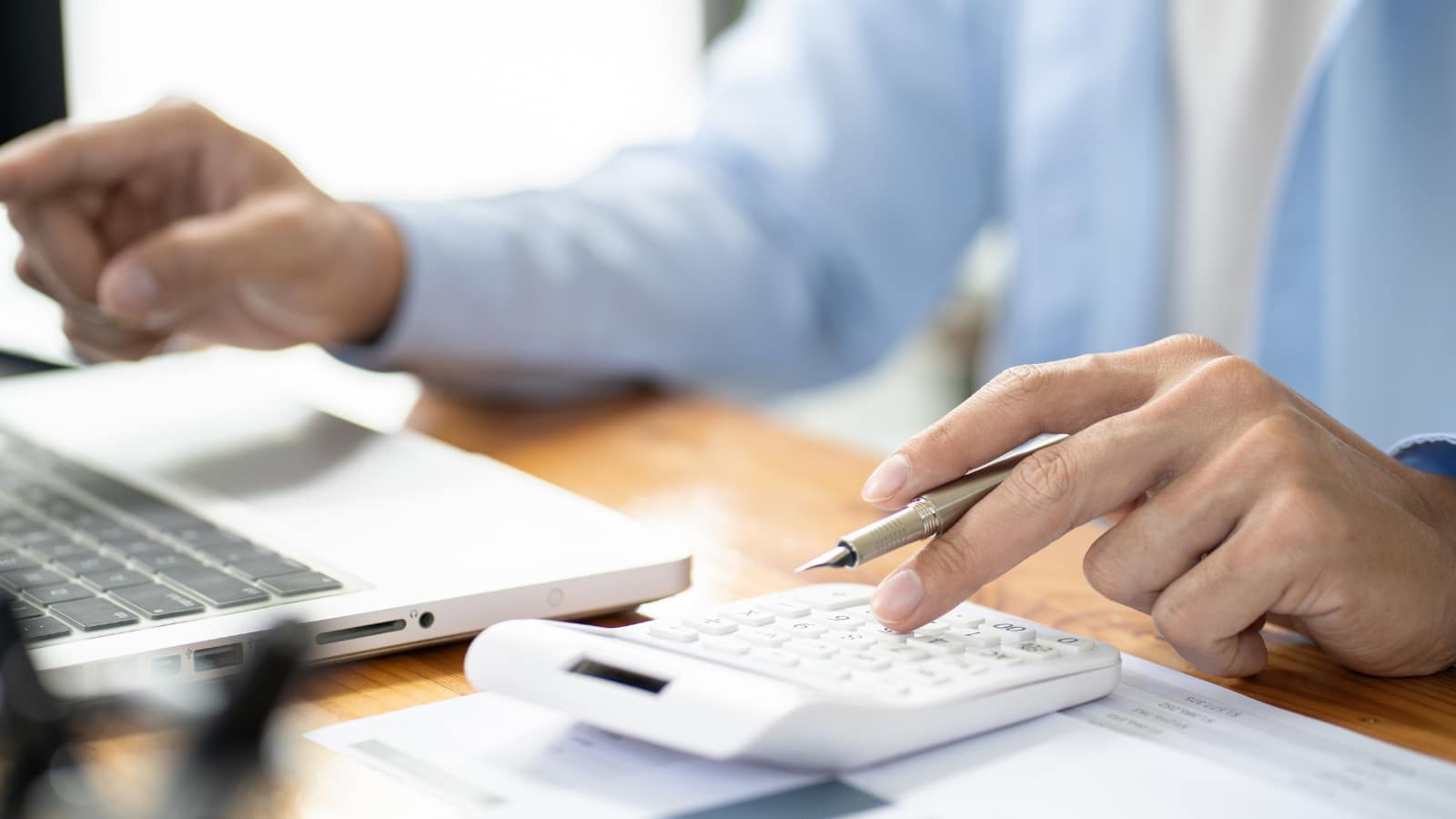 AI in e-commerce: data analysis and customer service automation AI in e-commerce – man in a light shirt analyzing data on a calculator by laptop