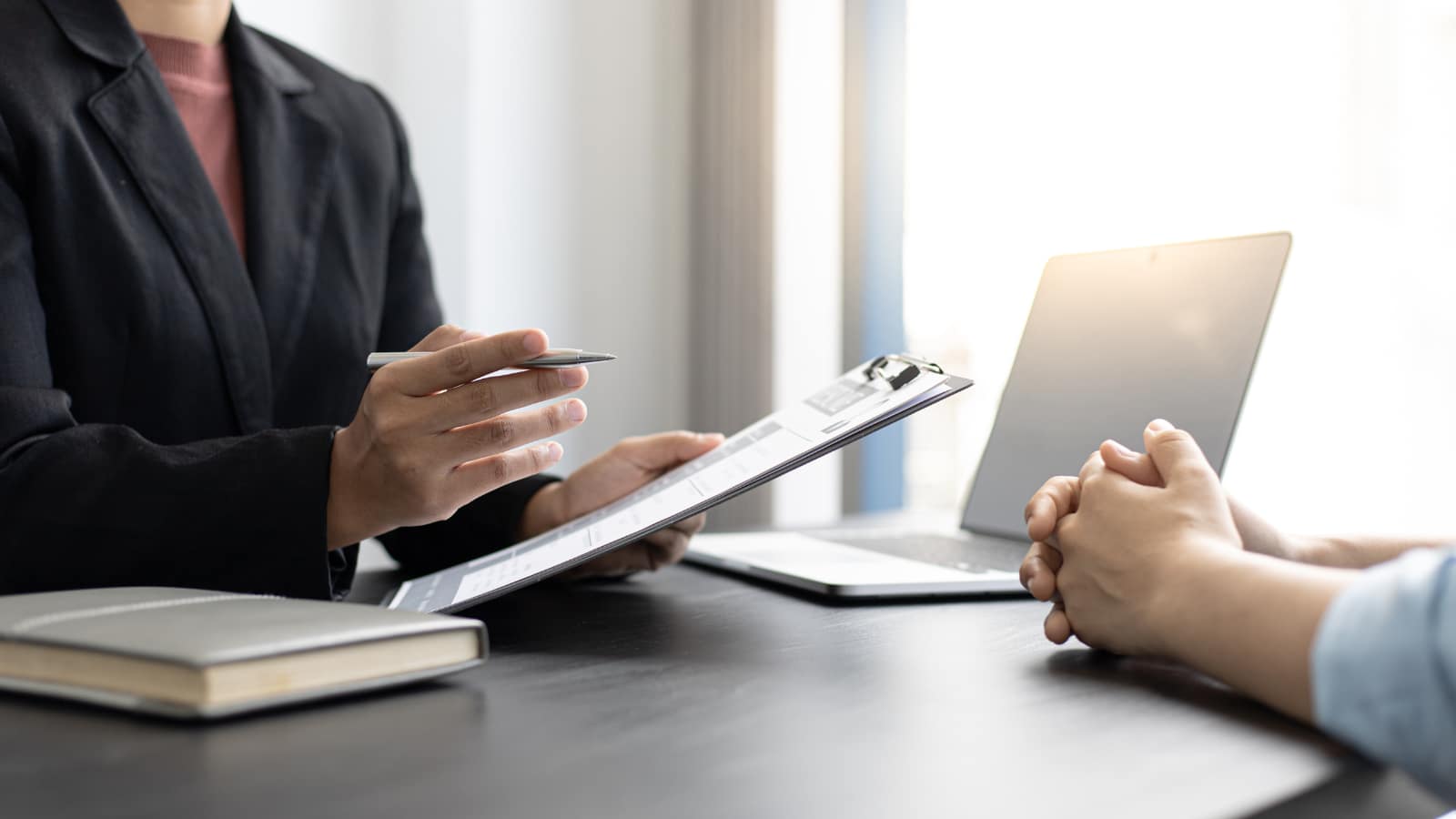 Jak wykorzystać AI w HR do rekrutacji i oceny pracowników – analiza danych podczas rozmowy Jak wykorzystać AI w HR do rekrutacji i oceny pracowników – dwie osoby przy biurku analizują dane na laptopie i w dokumentach