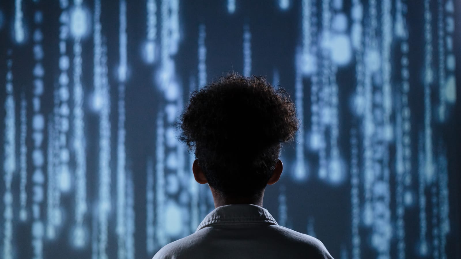 Generative Engine Optimization (GEO) – analiza danych AI Człowiek stojący przed wielkim ekranem z przewijającymi się rzędami świecących cyfr – wizualizacja Generative Engine Optimization (GEO) i pracy z AI