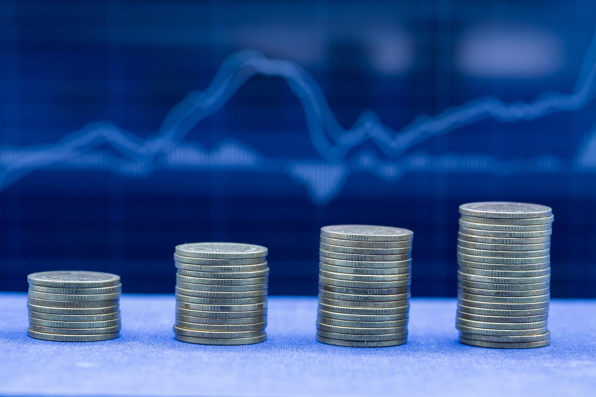 Stacks of evenly arranged coins against a chart on a screen