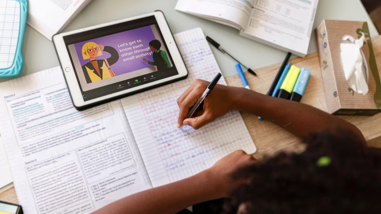 Dziecko podczas nauki przy biurku z książkami i tabletem – wykorzystanie AI w edukacji