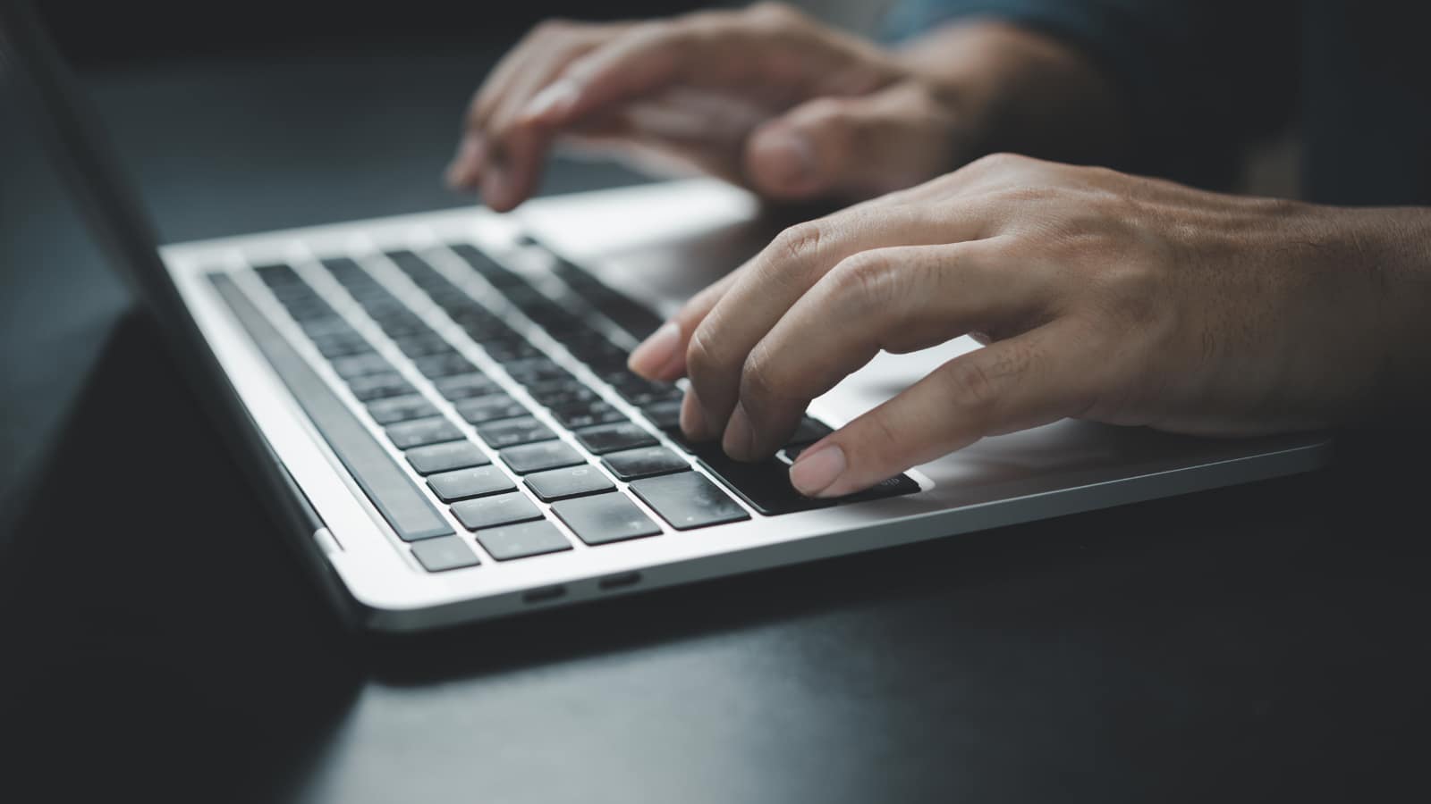 Automatyzacja pracy freelancera – dłonie piszą e-mail na klawiaturze laptopa z wykorzystaniem AI