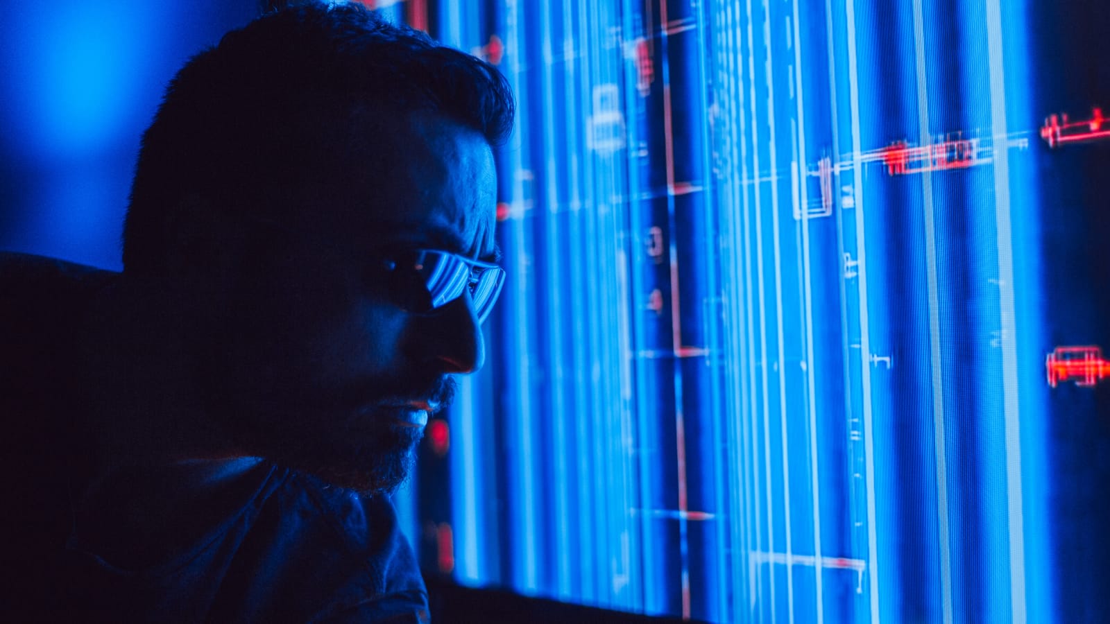 Człowiek w okularach wpatrujący się w monitor w blasku ekranu, symbolizujący ekspercką pracę z Generative Engine Optimization (GEO) i AI Engine Optimization (AEO)