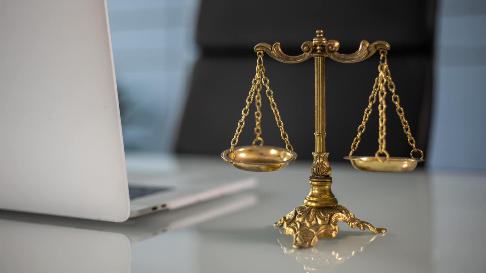 Legalność sprzedaży online – waga symbolizująca prawo, laptop w tle