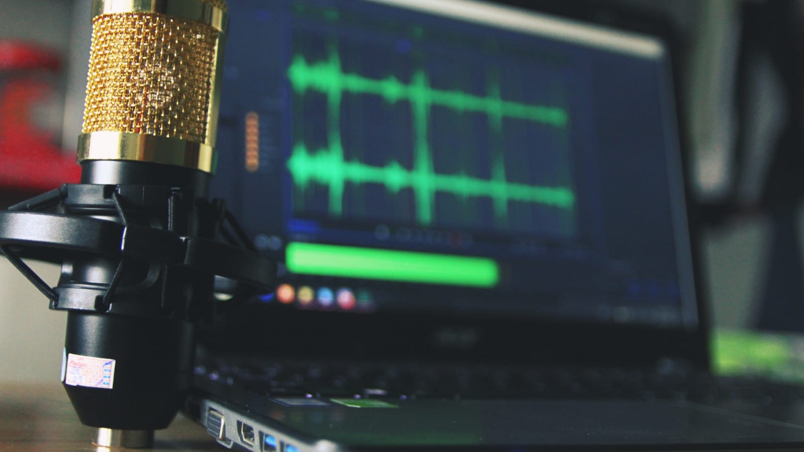 Zarabianie na podcastach AI – mikrofon w pierwszym planie, w tle laptop nagrywający dźwięk